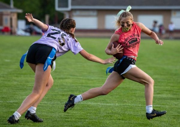 Number 25, Hailey Hetrick (junior) attempts to pull number 26, Faith Warner’s (senior) flag during the 2023 Powderpuff game. This new club will help the girls to prepare for this annual competition. 