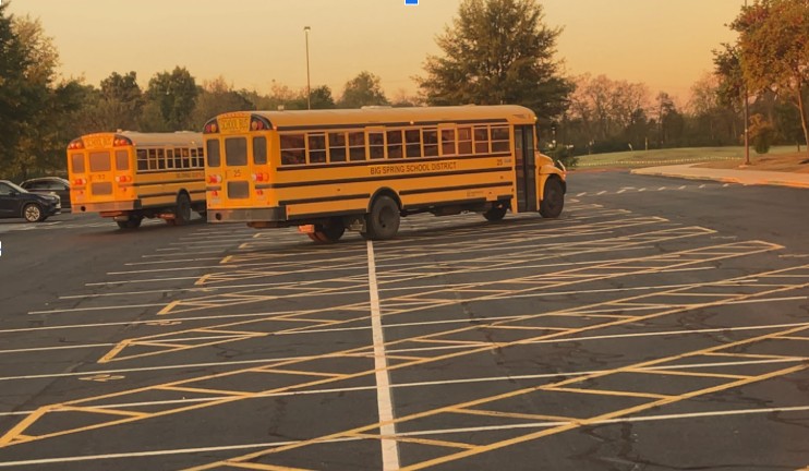 Buses are arriving at the high school to start off the school day. 
Buses are getting to school early so that students can get to class on time. 

